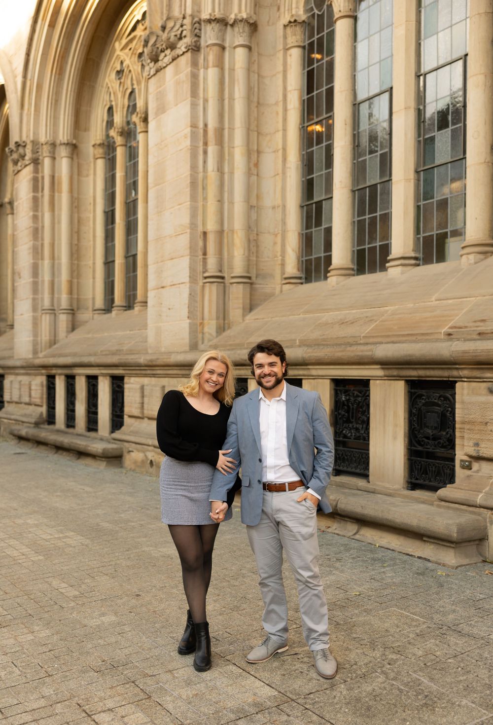 Couple standing in front of ornate gothic stone building architecture.