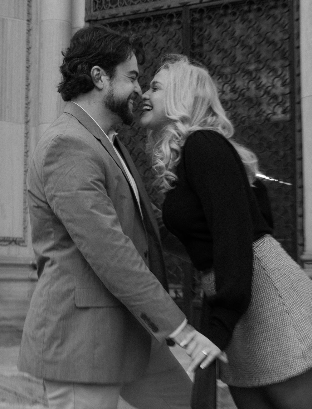 A black and white romantic moment captured against an ornate door background.