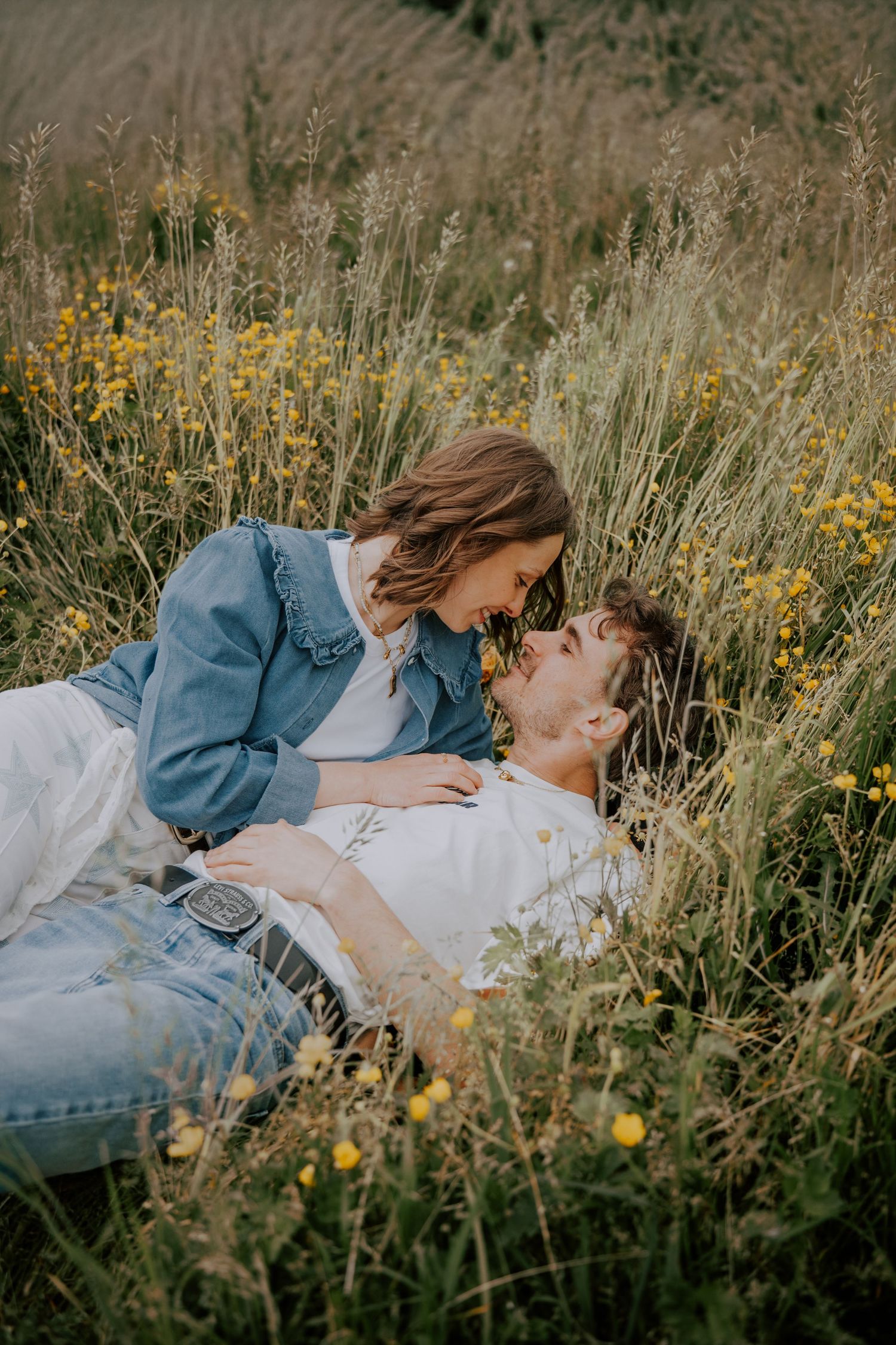 A happy couple embraces outdoors during a sunset photoshoot in a natural wooded setting.