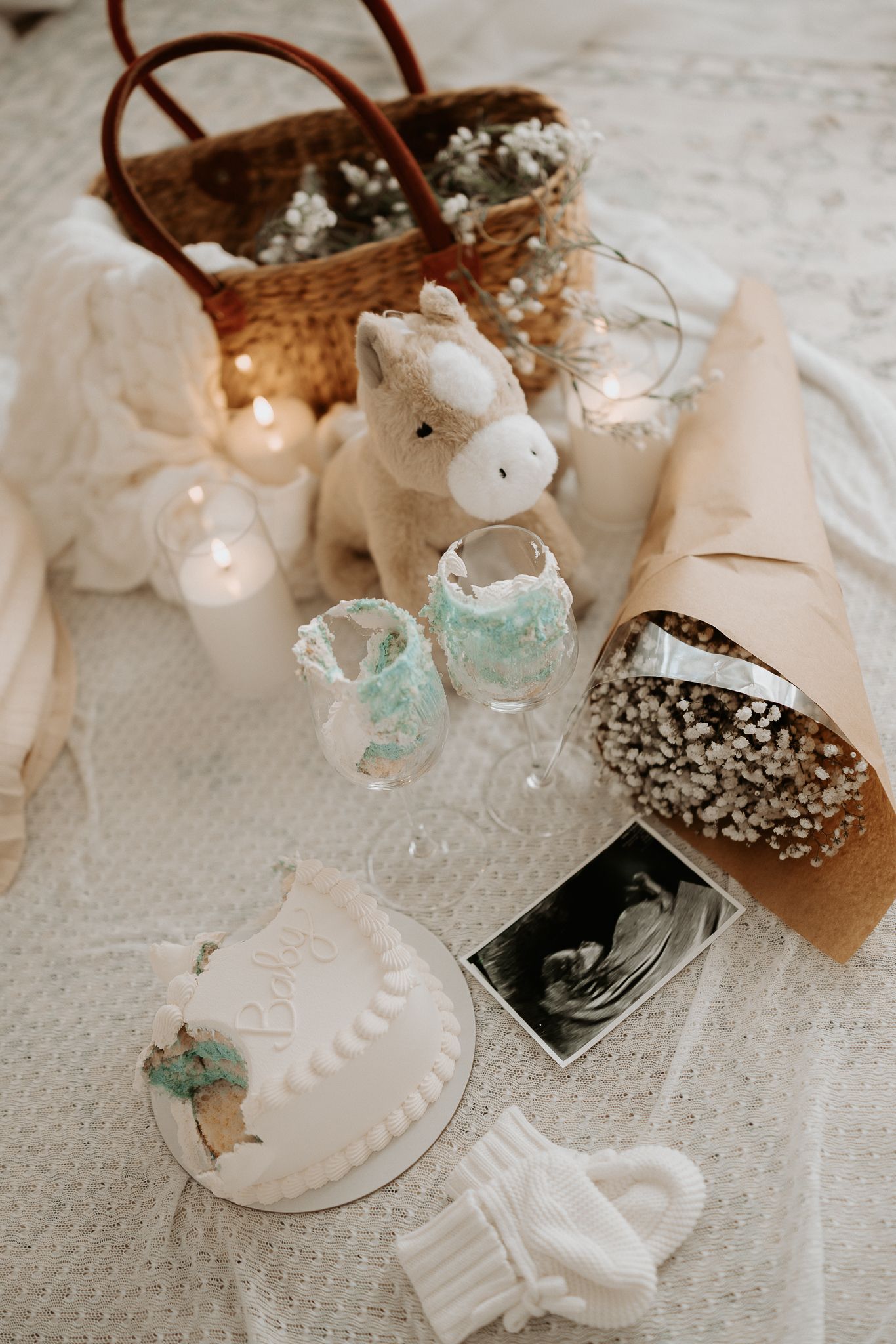 A sleeping newborn swaddled in white fabric on soft bedding.