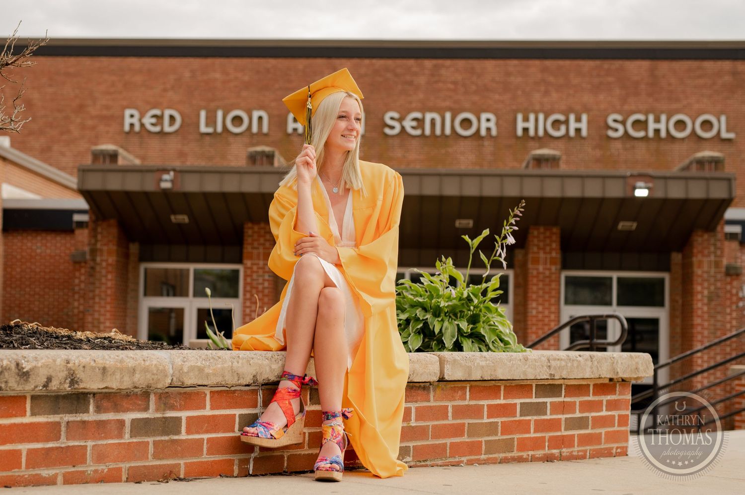 A graduate poses in a yellow cape outside Red Lion Senior High School entrance.
