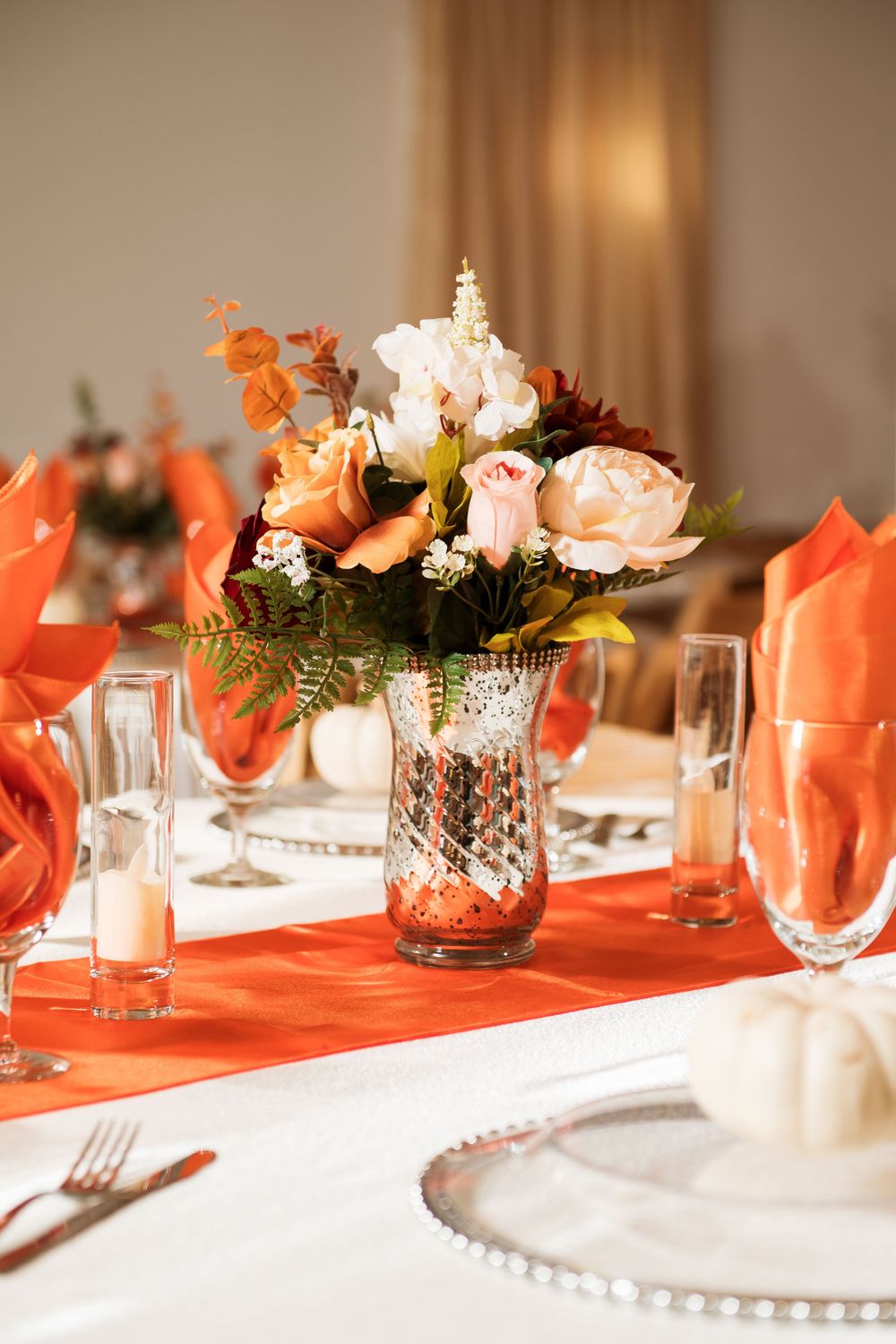 Elegant table setting with coral napkins and centerpiece featuring peach roses in a cut crystal vase.