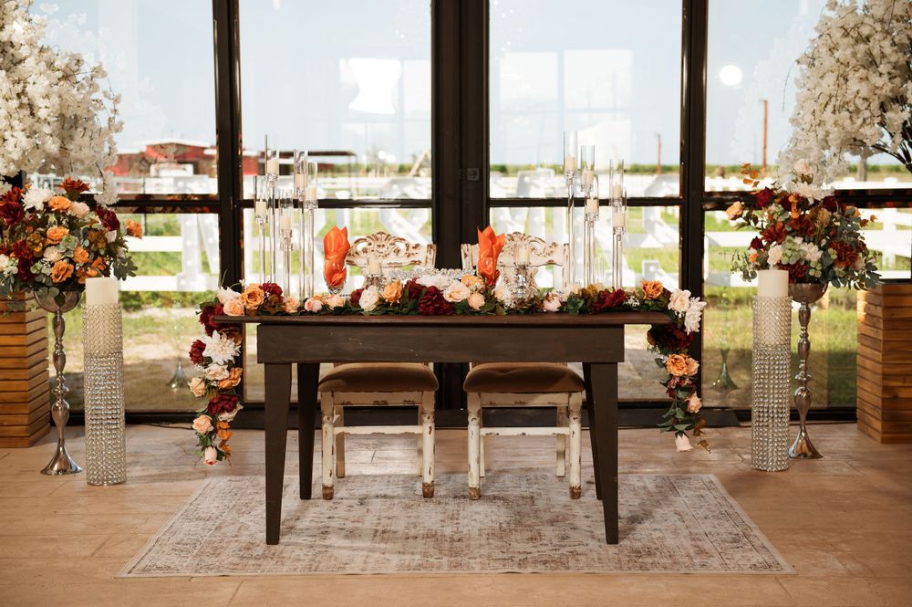 Intimate sweetheart table with fall-themed floral arrangements and hanging lights in a rustic indoor space.