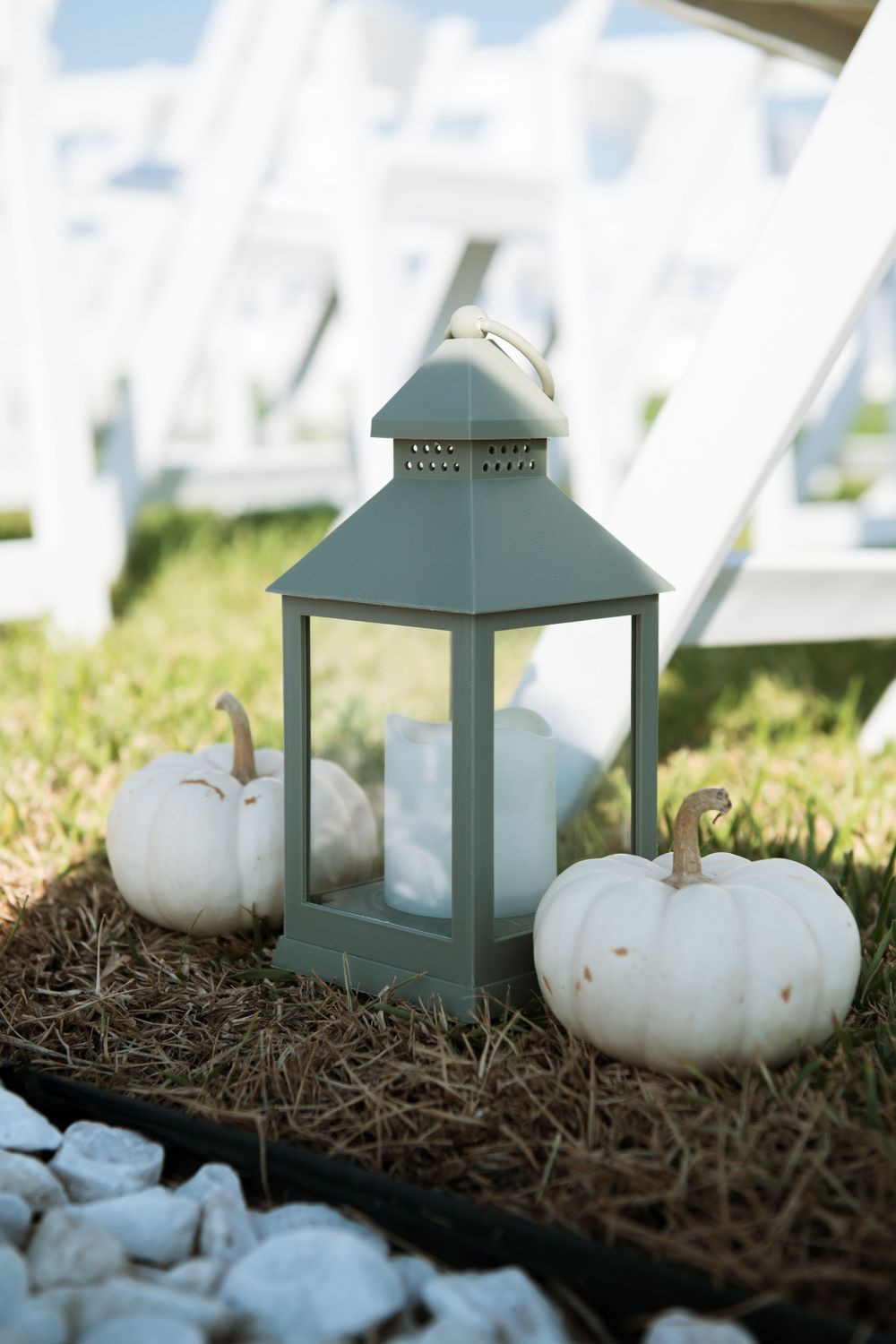 White decorative lantern with white pumpkins and stones creating autumn-themed wedding decor.