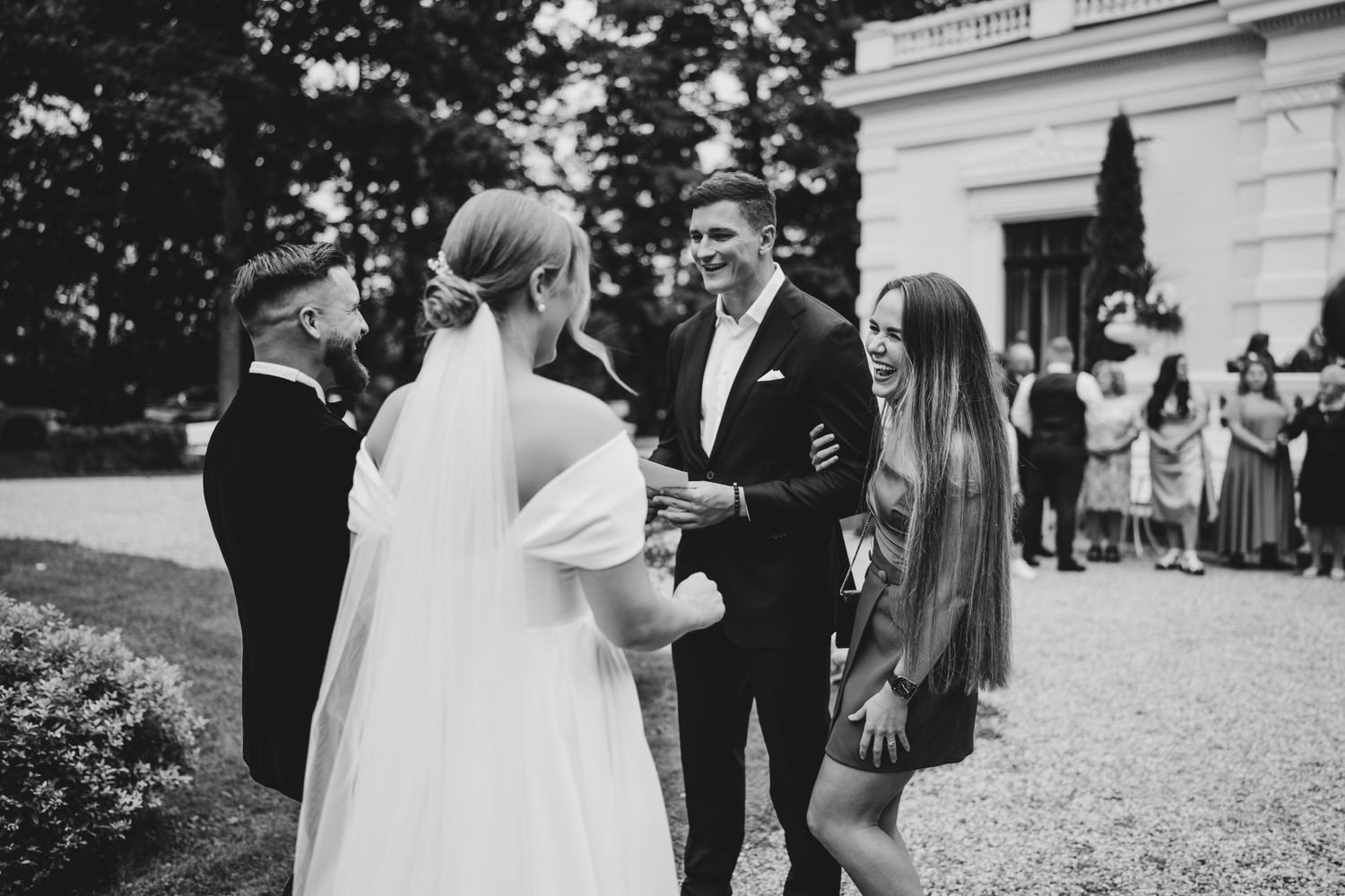 Wedding party enjoying festivities on the grounds of an elegant white mansion.