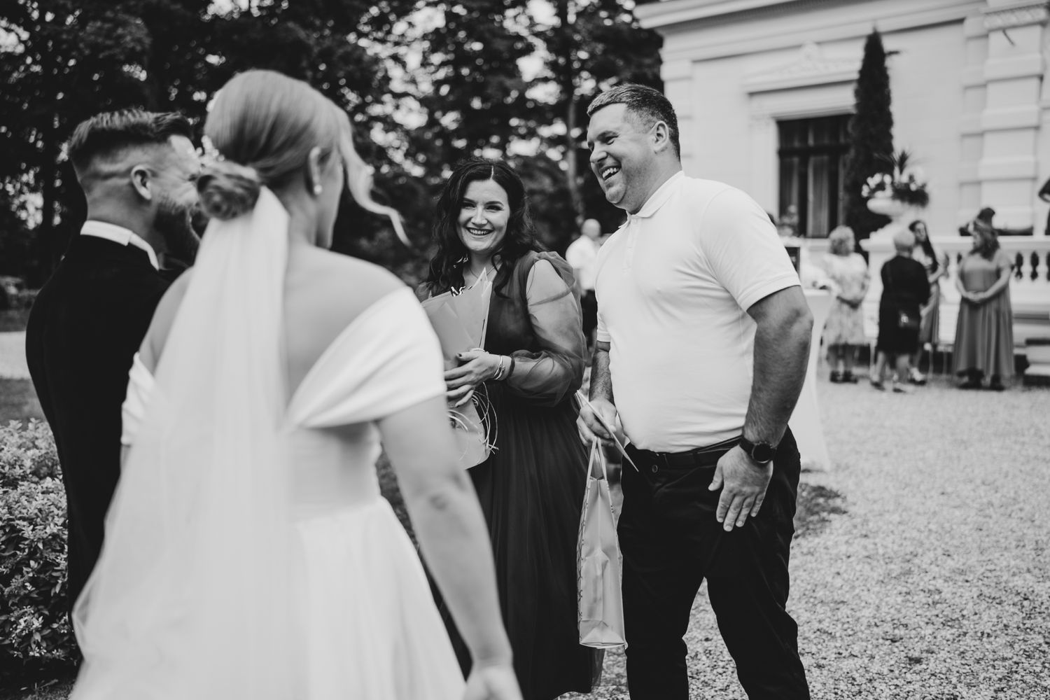 Joyful wedding celebration with guests gathered outside a historic white building.