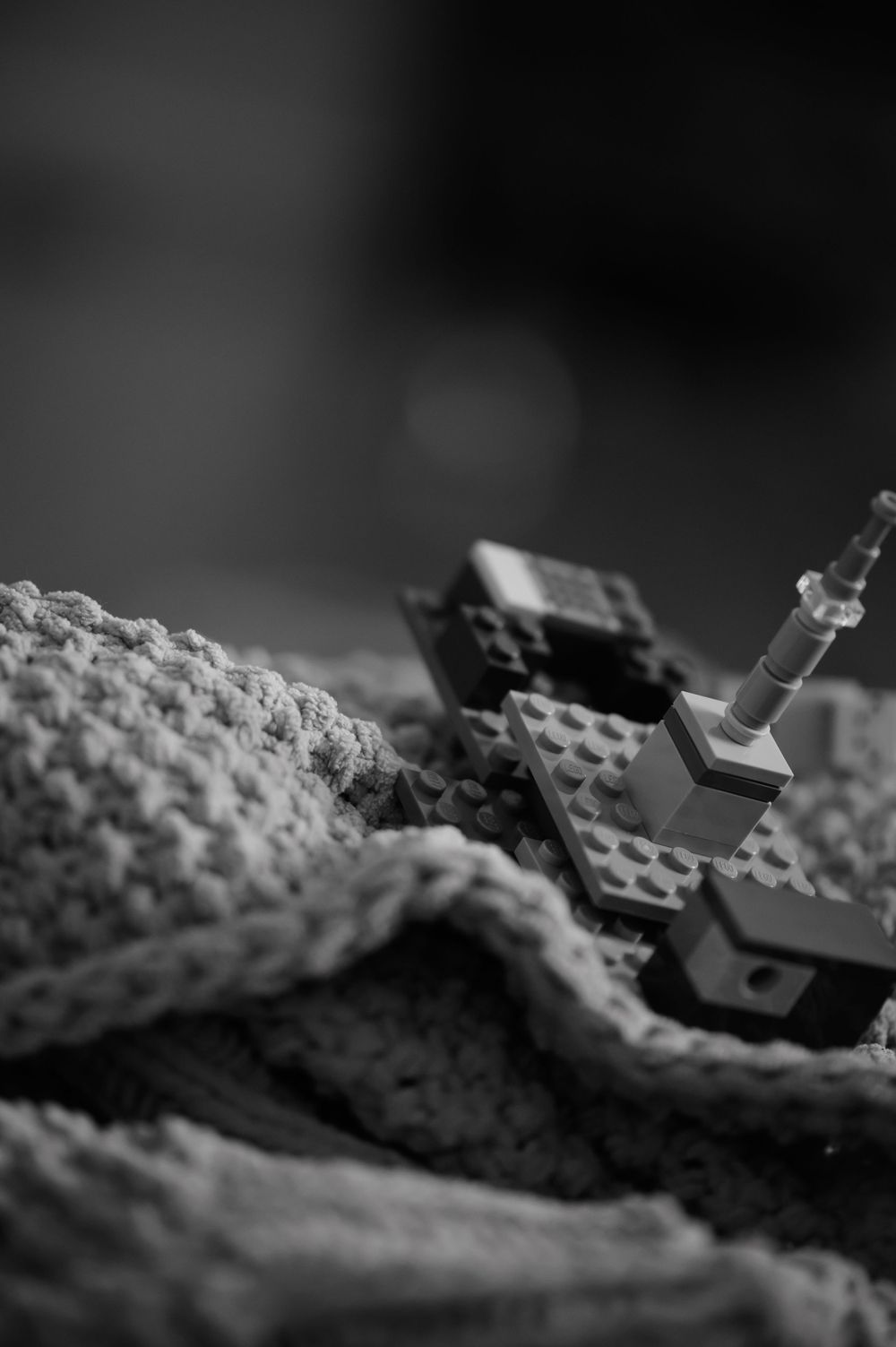 Black and white macro shot of LEGO pieces on textured fabric surface.