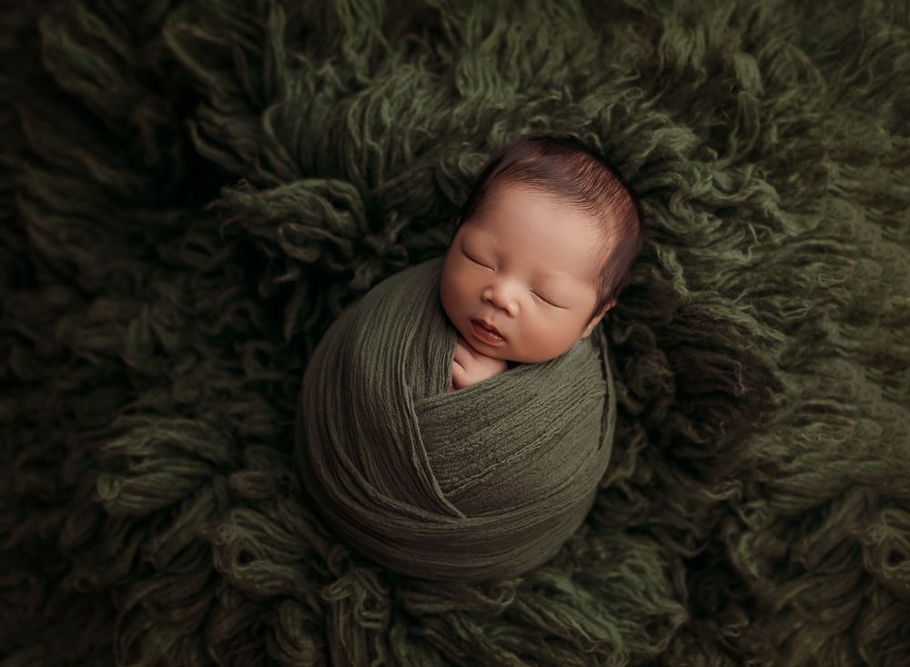 newborn-baby-boy-wrapped-in-green-laying-on-green-flokati-at-his-newborn-session-in-tulsa-ok