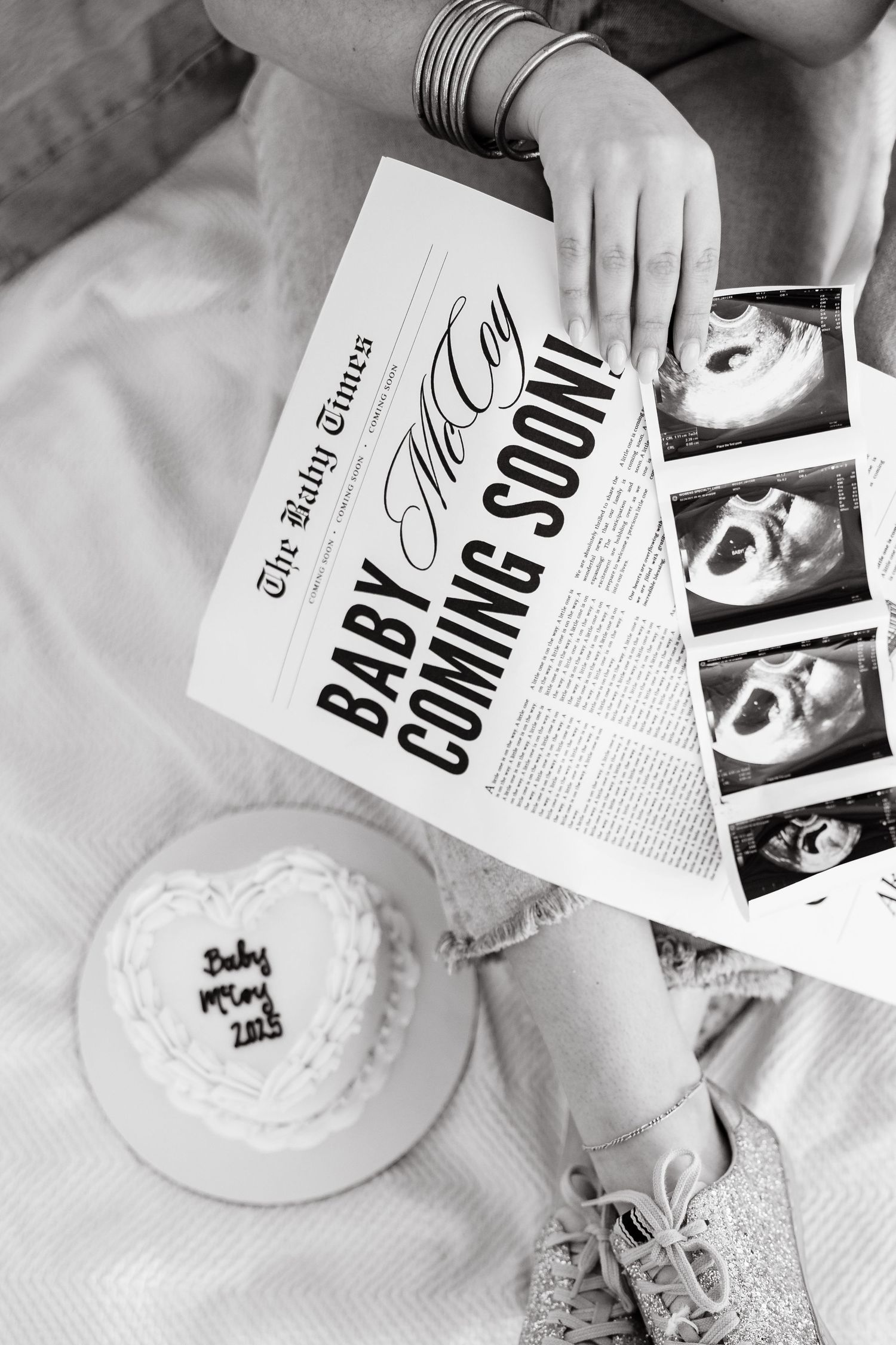 A couple holding ultrasound photos outdoors during a pregnancy announcement.