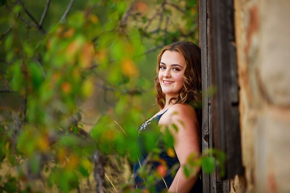A series of outdoor portrait shots showing someone posing near a rustic wooden structure surrounded by green foliage.