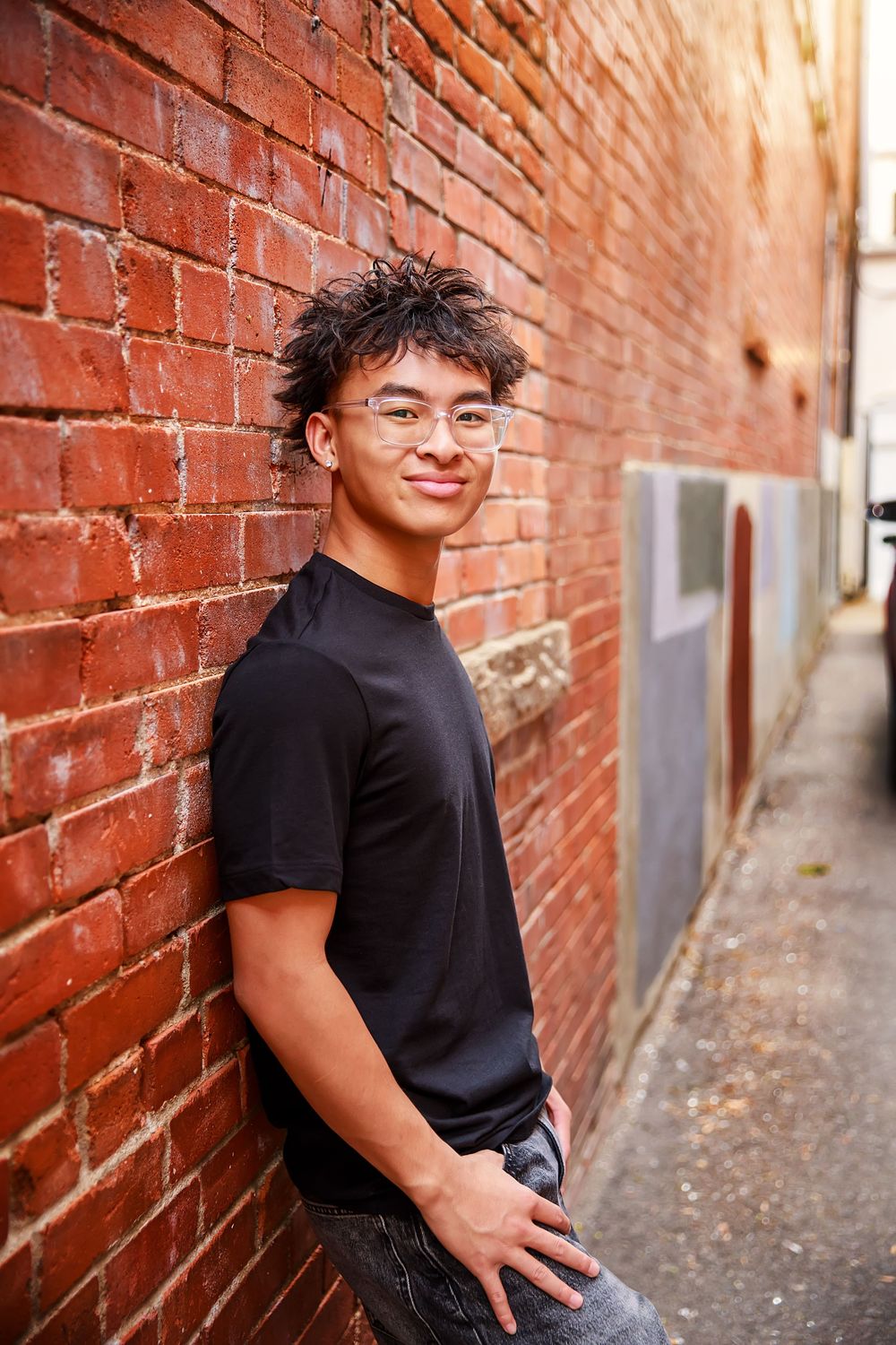 A series of portrait photos taken against a red brick wall in an urban alleyway setting.