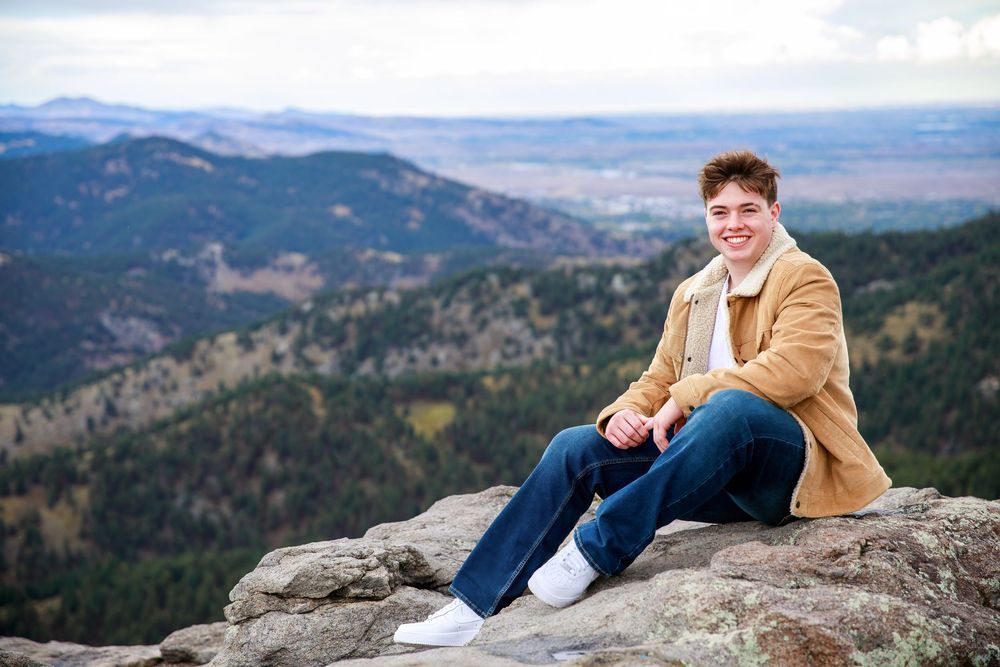 Senior portrait session captured on a scenic mountain overlook with sweeping valley views in the background.