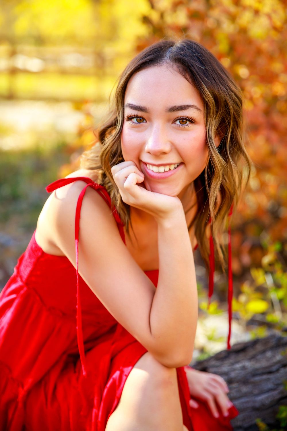 A autumn portrait in red dress with golden foliage in background.