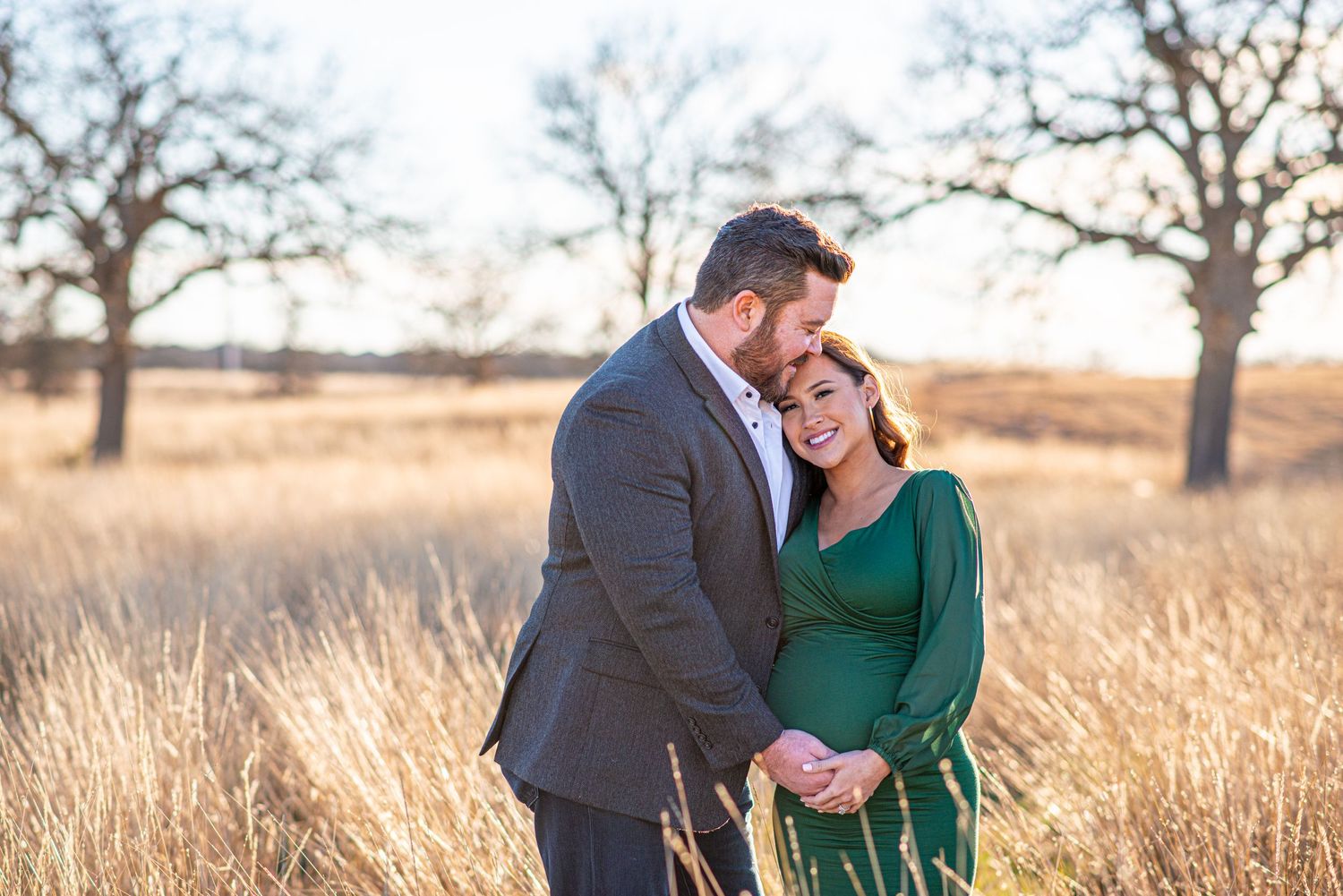 Sweet candid moment between couple during sunset maternity photoshoot in nature.