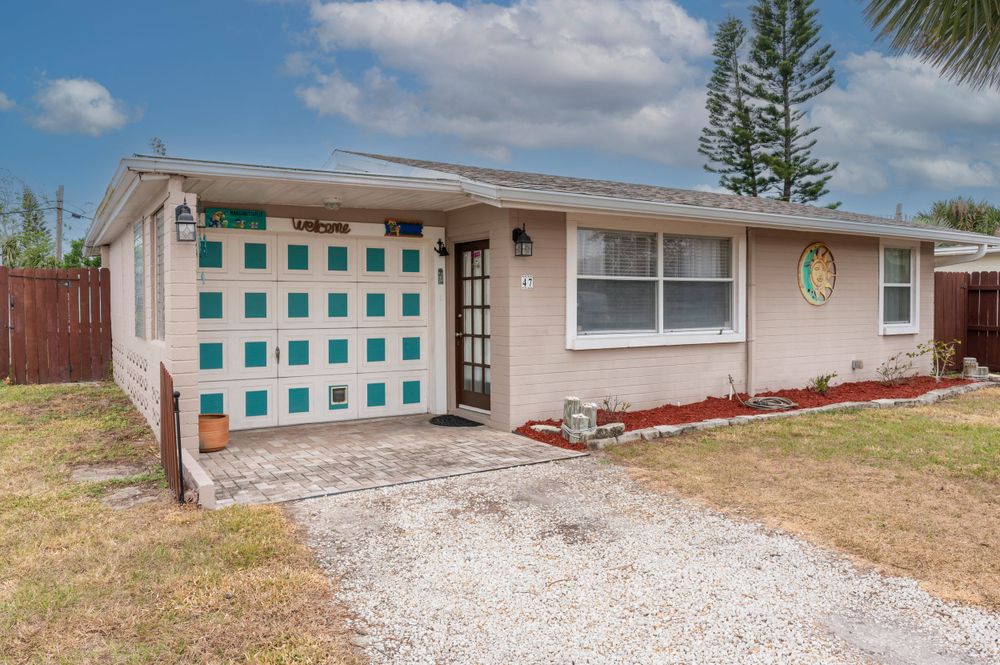 Front view of a mid-century home featuring distinctive turquoise and white checkered garage door.