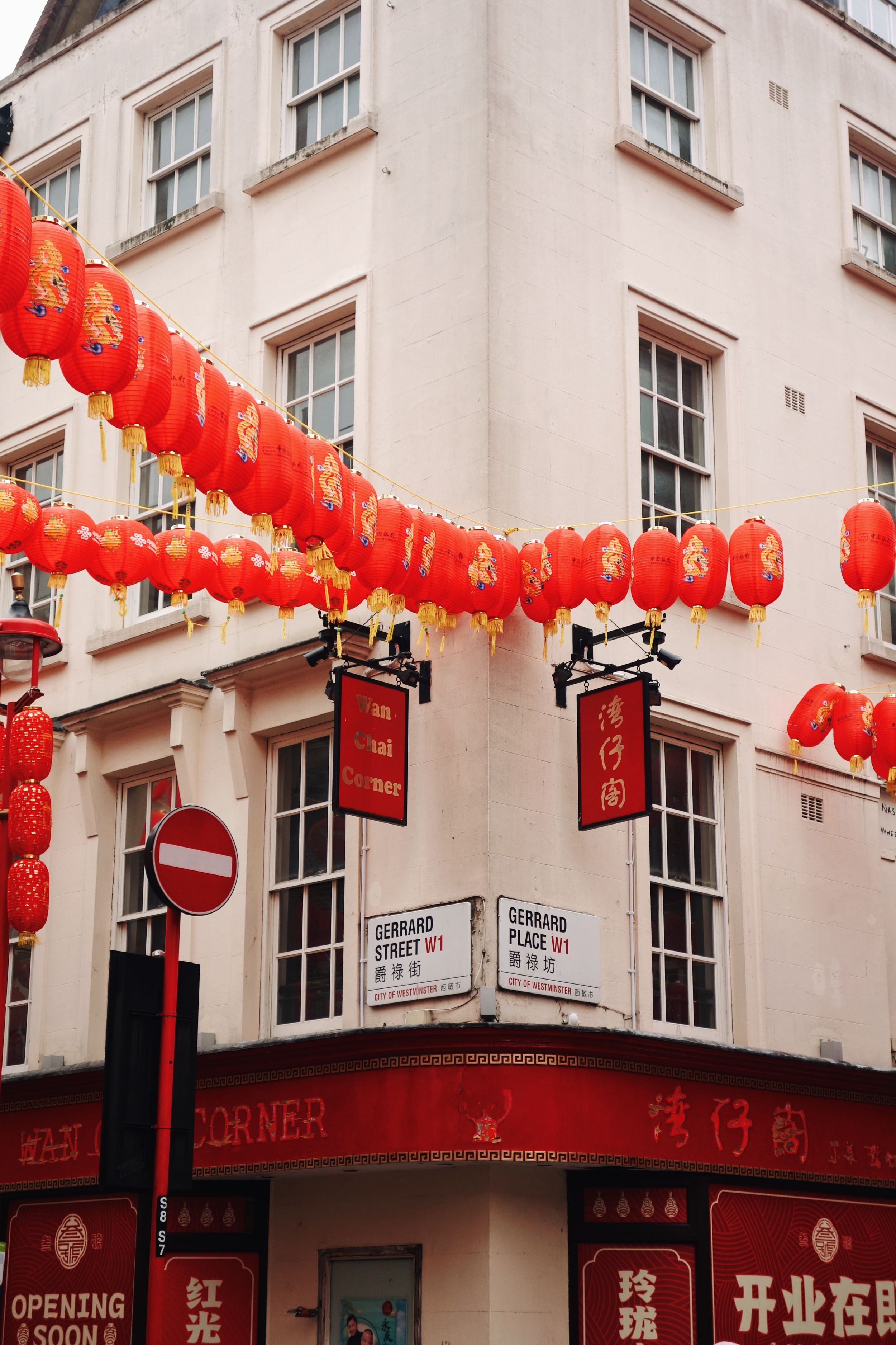 Red Chinese lanterns decorate a corner building in London's Chinatown with cream walls and sash windows.
