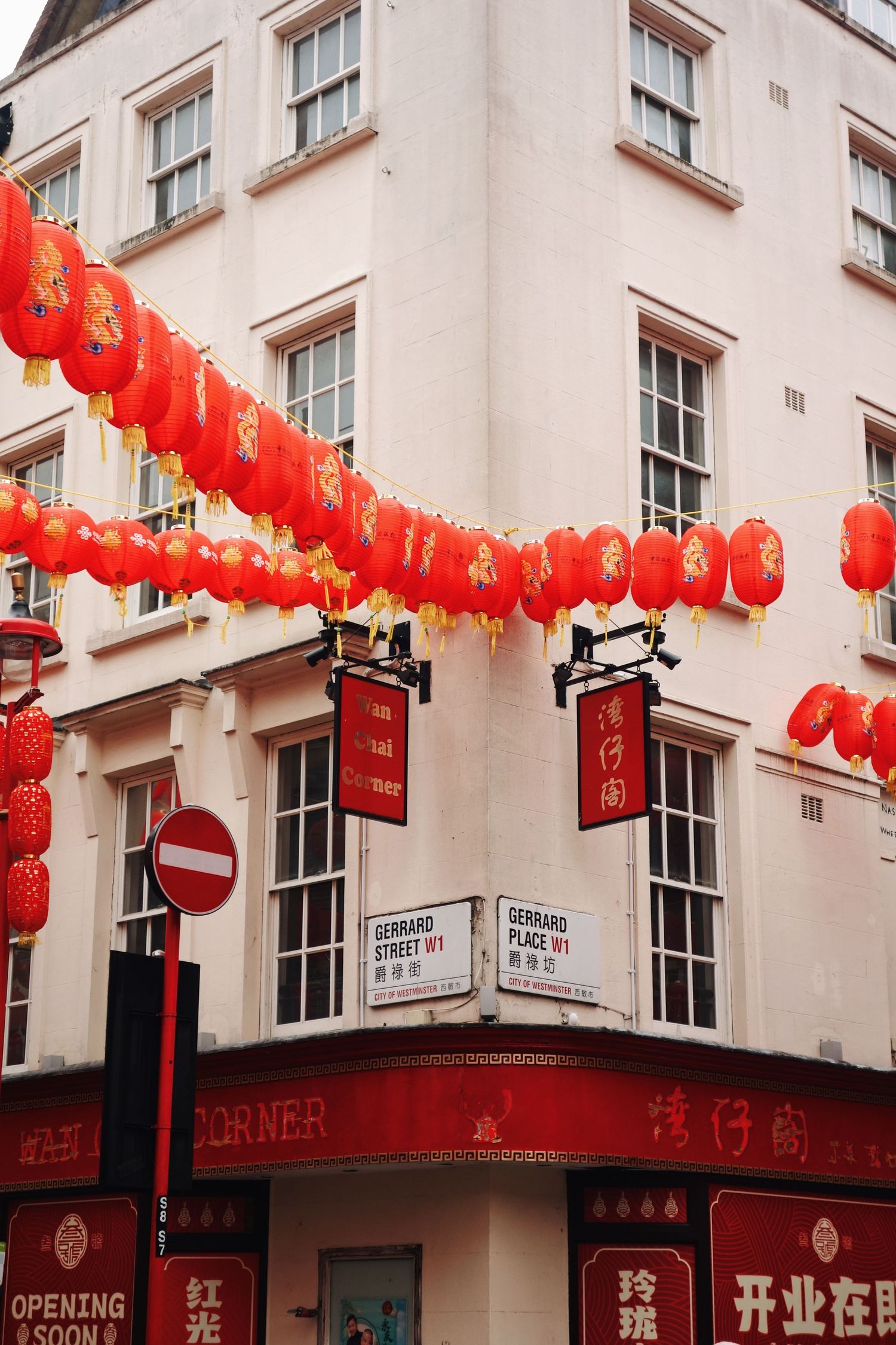 Red Chinese lanterns decorate a corner building in London's Chinatown with cream walls and sash windows.