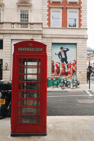 Iconic red London telephone booth stands in front of brick building with colorful street art mural and parked bicycle.