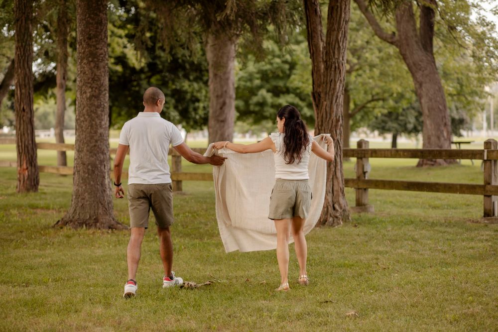 Couple lay out blanket on ground at Lake Ontario Park, Kingston, ON, Ca.