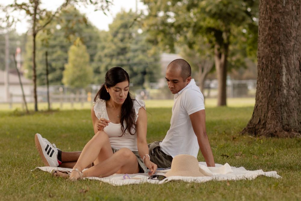 Couple sitting on a white picnic blanket in the evening sunshine, Lake Ontario Park, Kingston, ON, Ca.