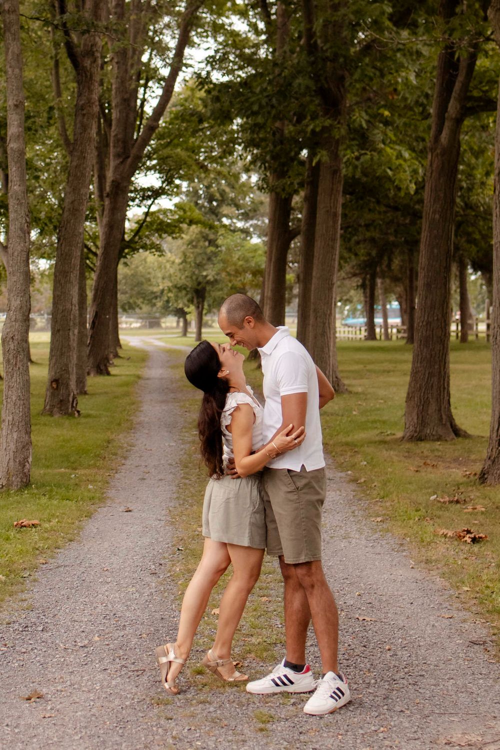 Couple walk the trails of Lake Ontario Park amongst the tall trees and greenspace in Kingston, Ontario, Canada.