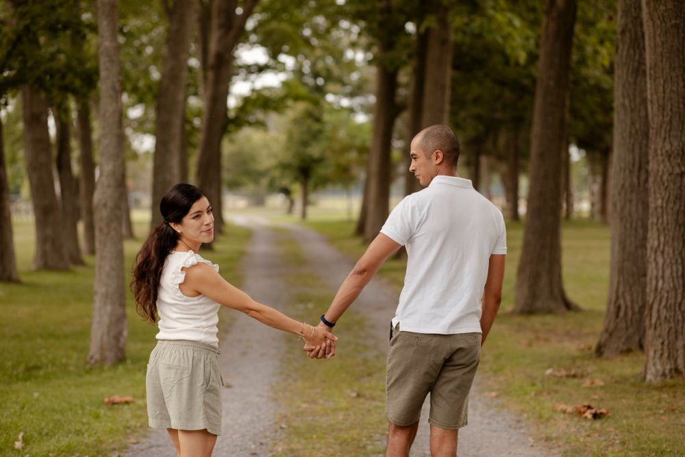 Couple walk the trails of Lake Ontario Park amongst the tall trees and greenspace in Kingston, Ontario, Canada.