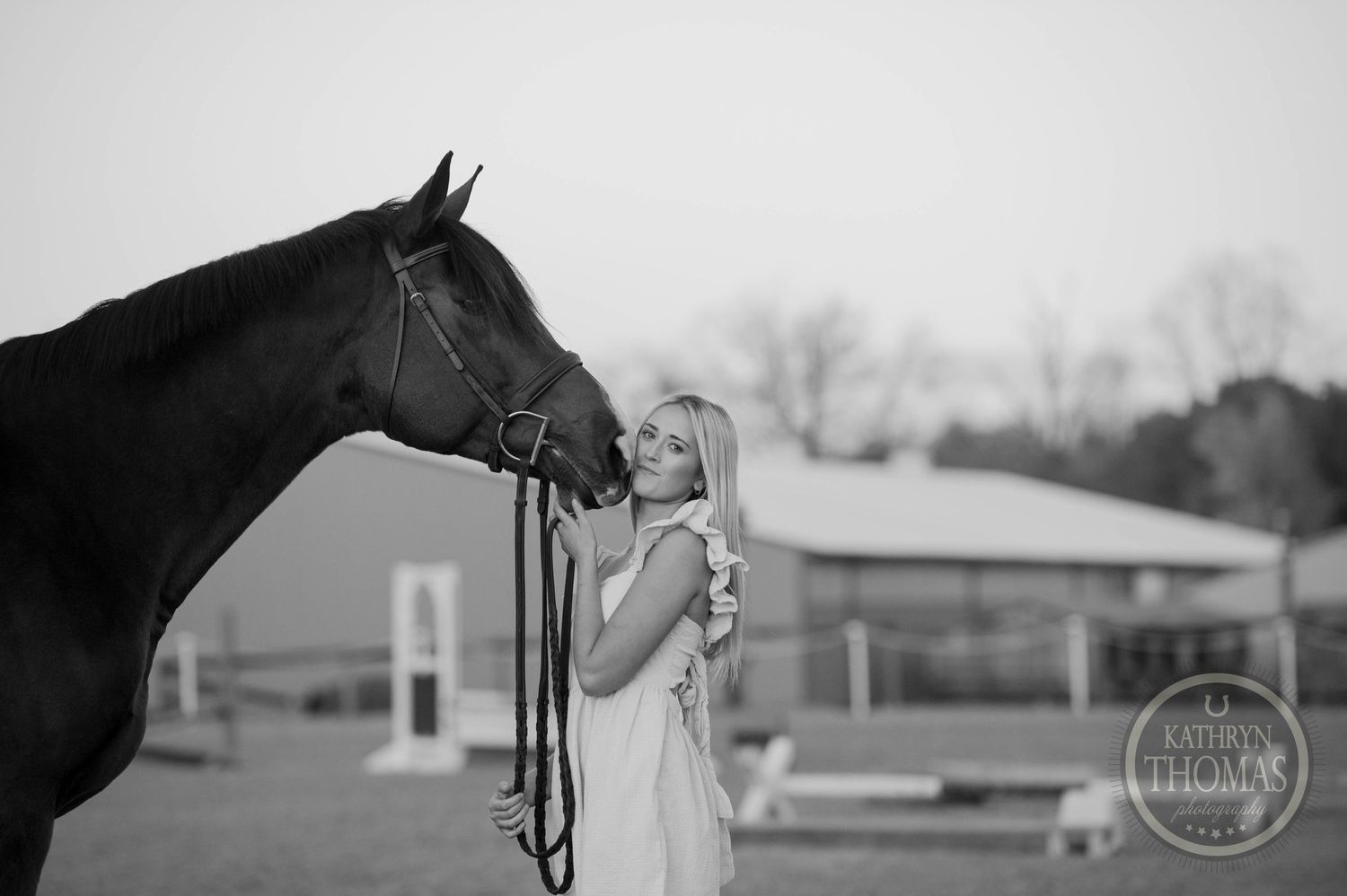 A black and white photo of someone in white sharing a moment with a horse.