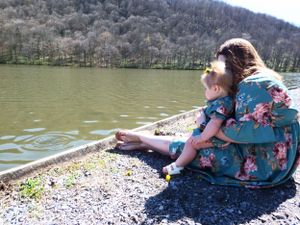 People sitting on rocky shoreline enjoying view of a mountain lake.