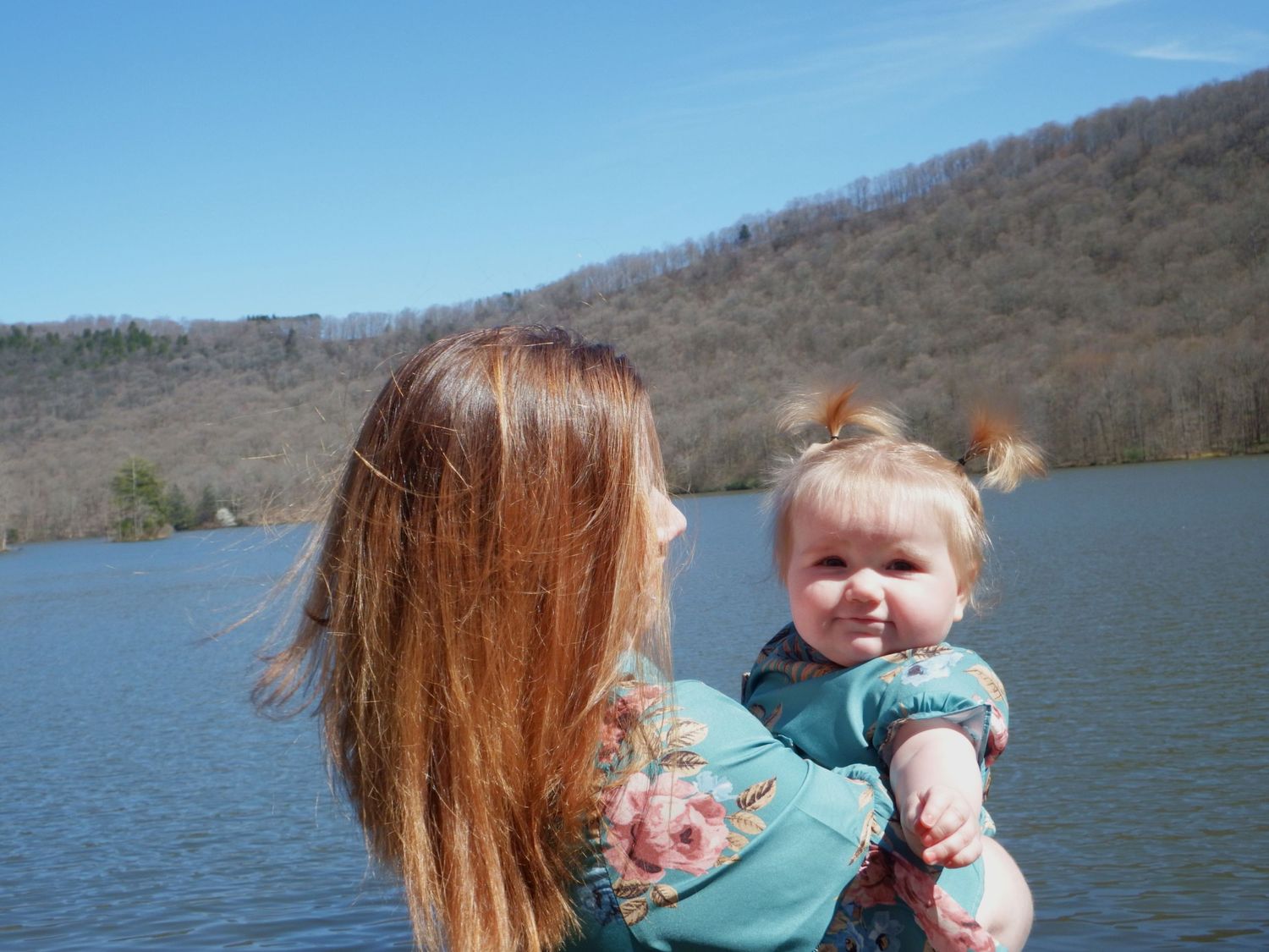 Family enjoying a peaceful moment by a lake on a sunny spring day.
