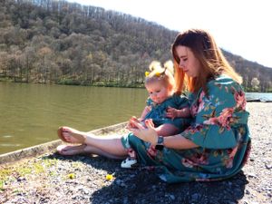 Family relaxing on rocky shore of mountain lake on sunny afternoon.