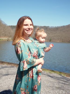 A pair enjoying a sunny day by the lake wearing matching floral dresses.