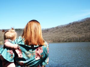 Two people in matching turquoise floral outfits standing by a serene lake.