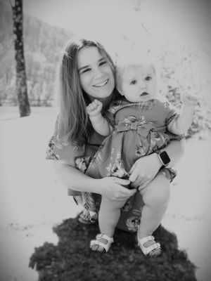 A black and white portrait of two people in matching floral dresses outdoors.