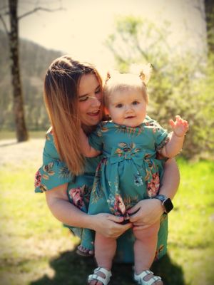 A sweet outdoor portrait showing two people in coordinating teal floral dresses.