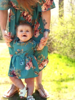 Close-up of coordinating teal floral dresses and sandals against a sunny spring background.
