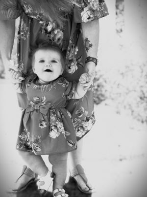 Black and white photo of matching floral dresses and helping hands.