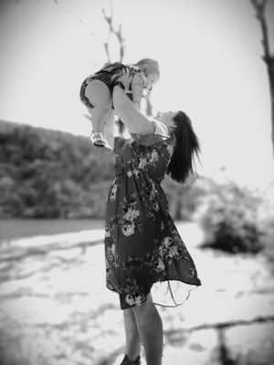 A black and white photo shows joyful lifting moment by a lake.