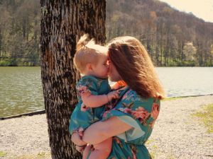 A sweet embrace captured by a tree trunk near a serene lake.