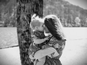 A tender black and white moment shared by a lake with mountains in the background.
