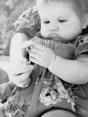 Black and white sequence showing a small child looking at a dandelion flower with curiosity.