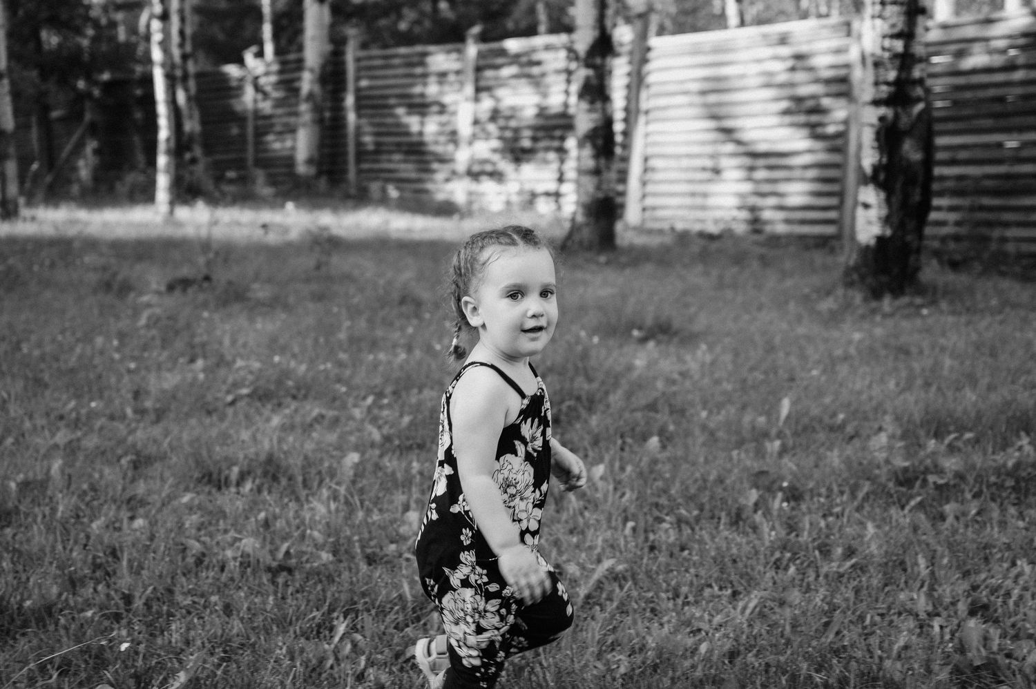 Child in floral dress standing in black and white garden setting.