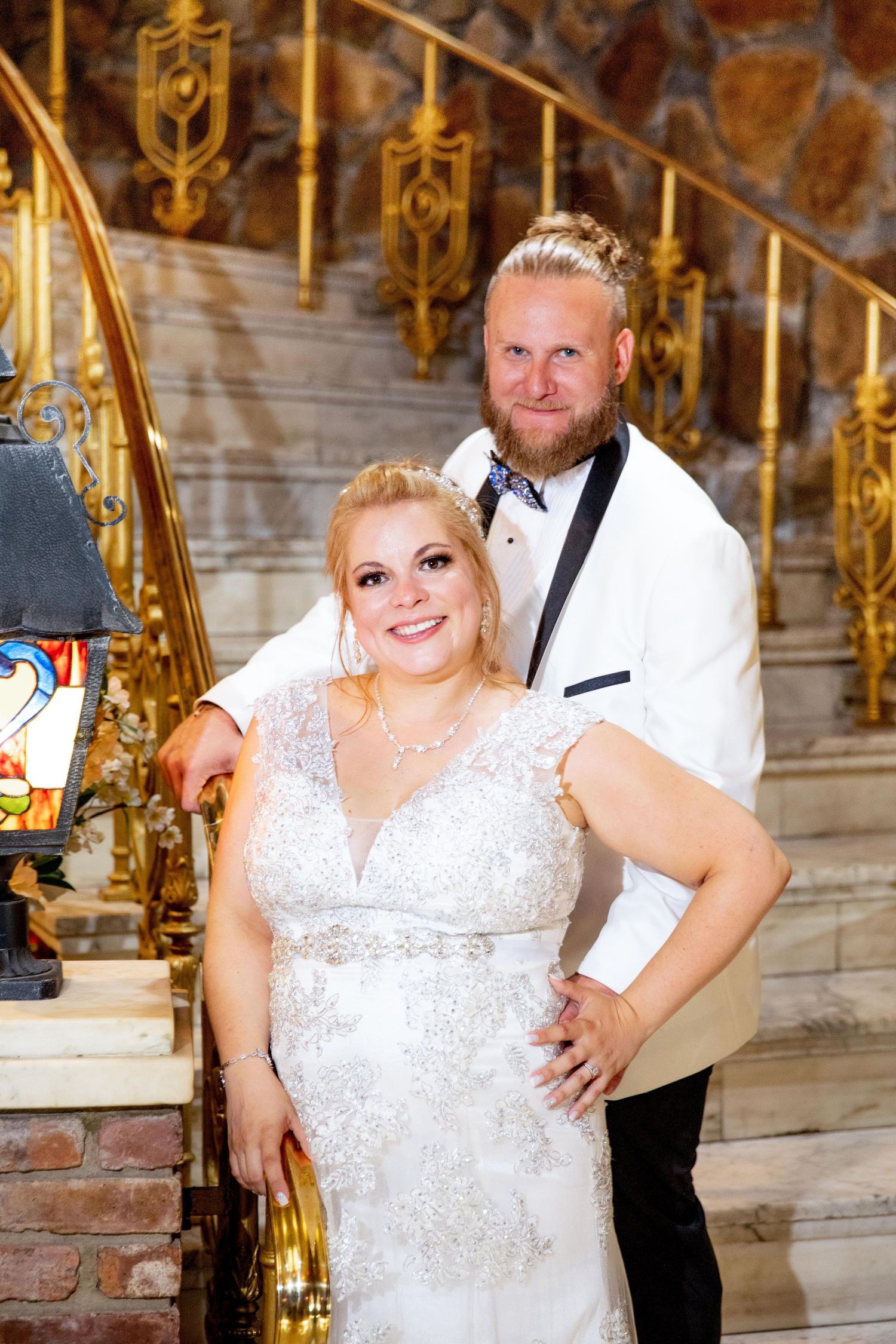 Elegant couple poses on ornate staircase during wedding celebration.