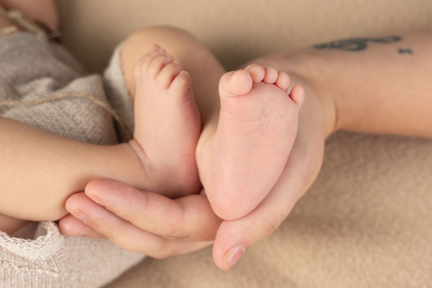 Close-up of tiny newborn baby feet being gently held by adult hands.