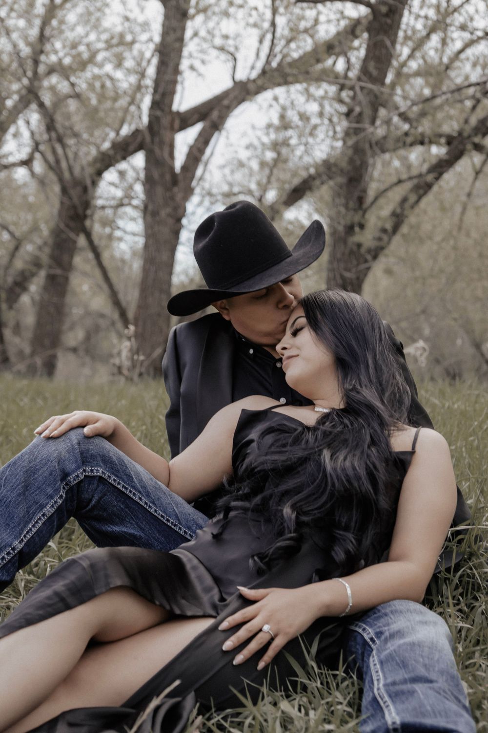 Couple sitting under trees snuggling