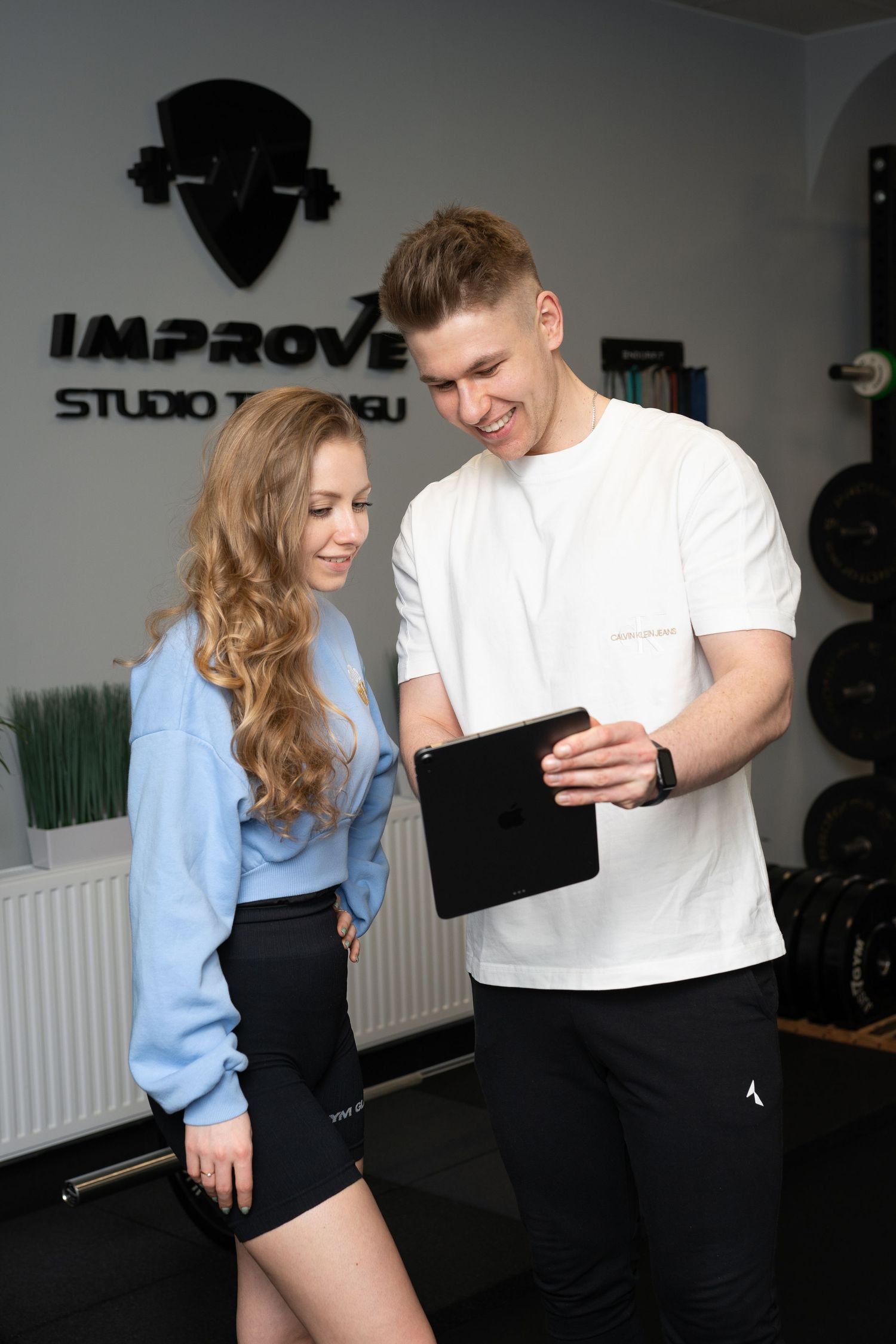 Two fitness professionals reviewing information on a tablet in a gym studio.