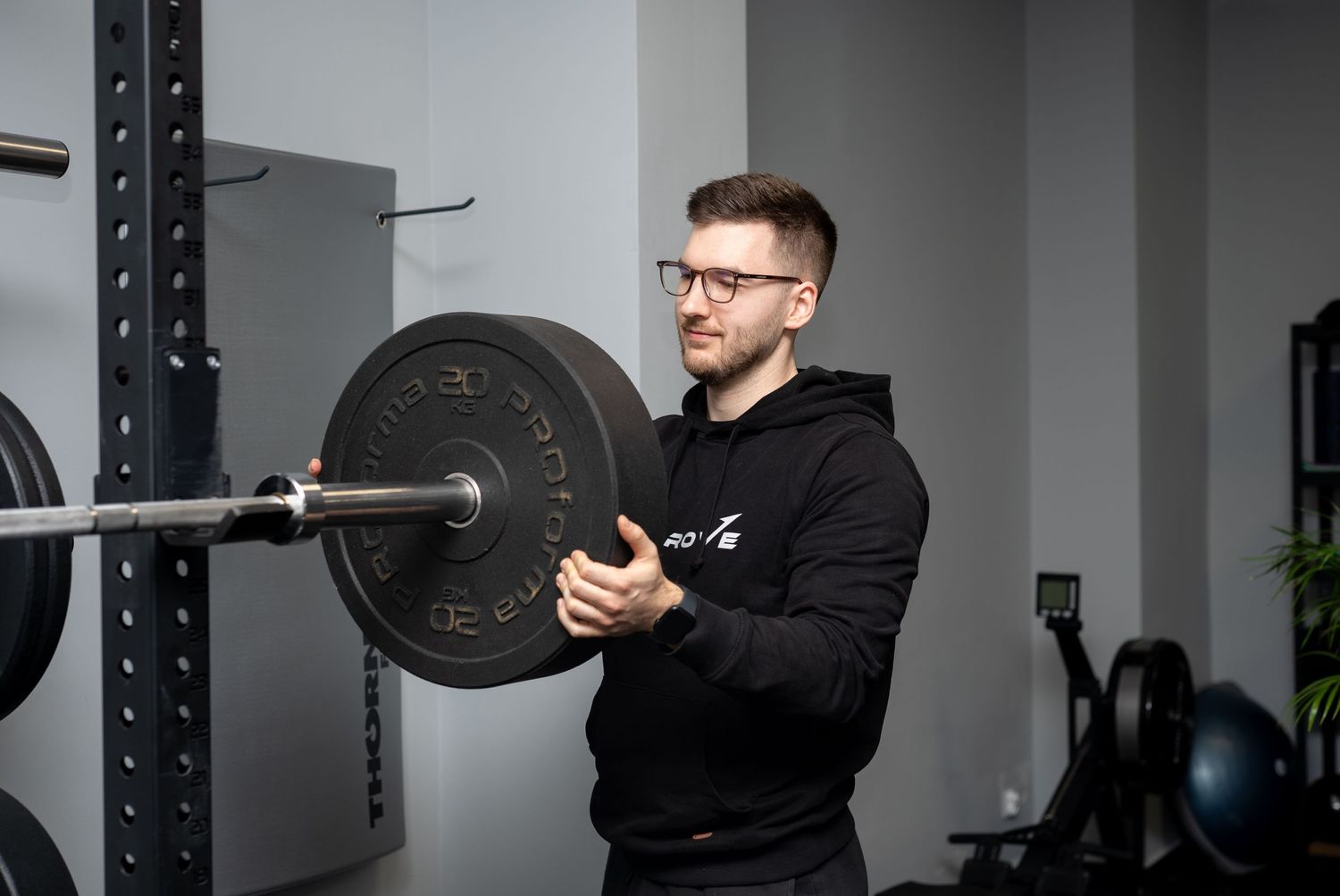 Personal trainer adjusting weights on a barbell in a modern gym setting.