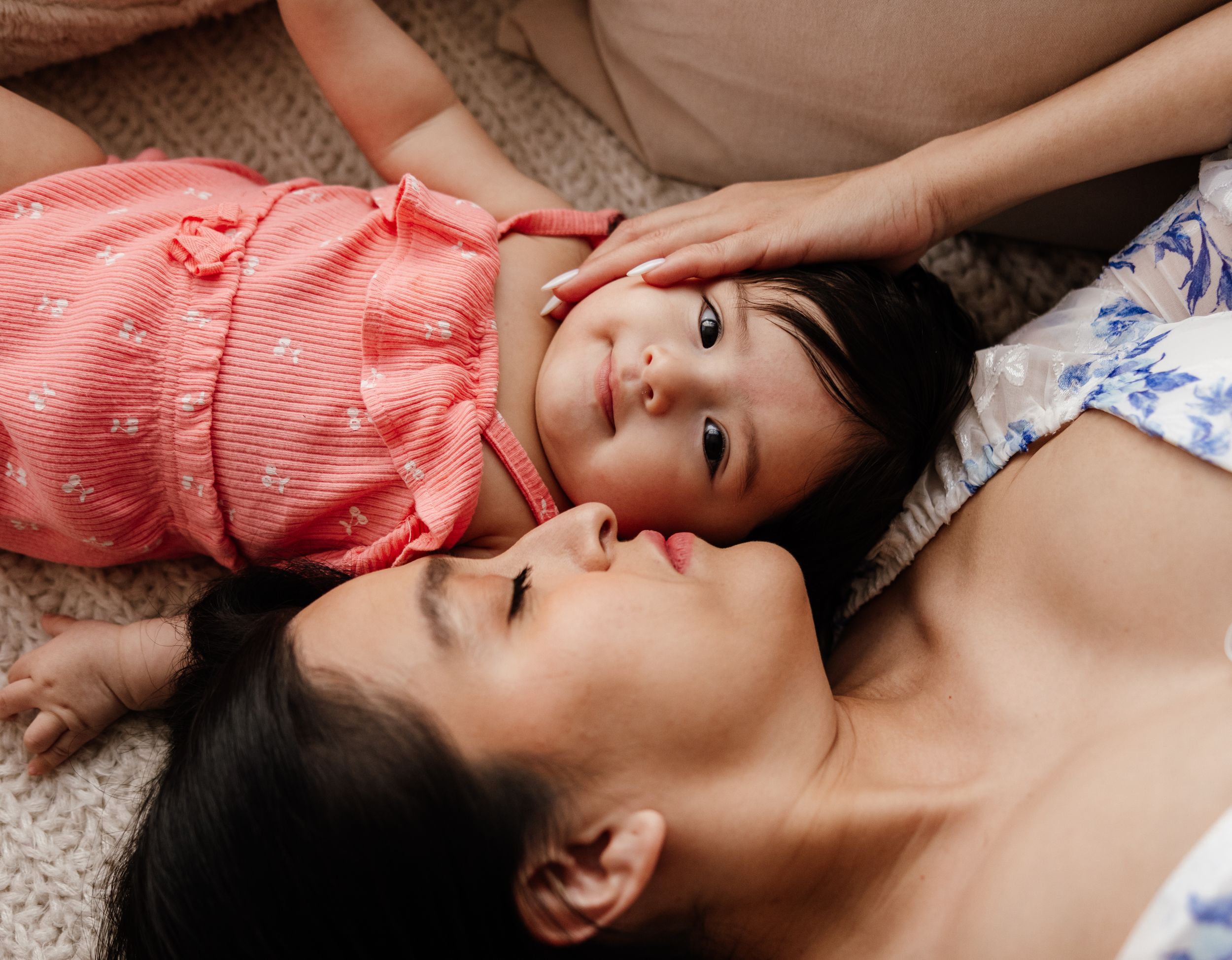 Two people laying on carpet together sharing a tender bonding moment in soft natural lighting.