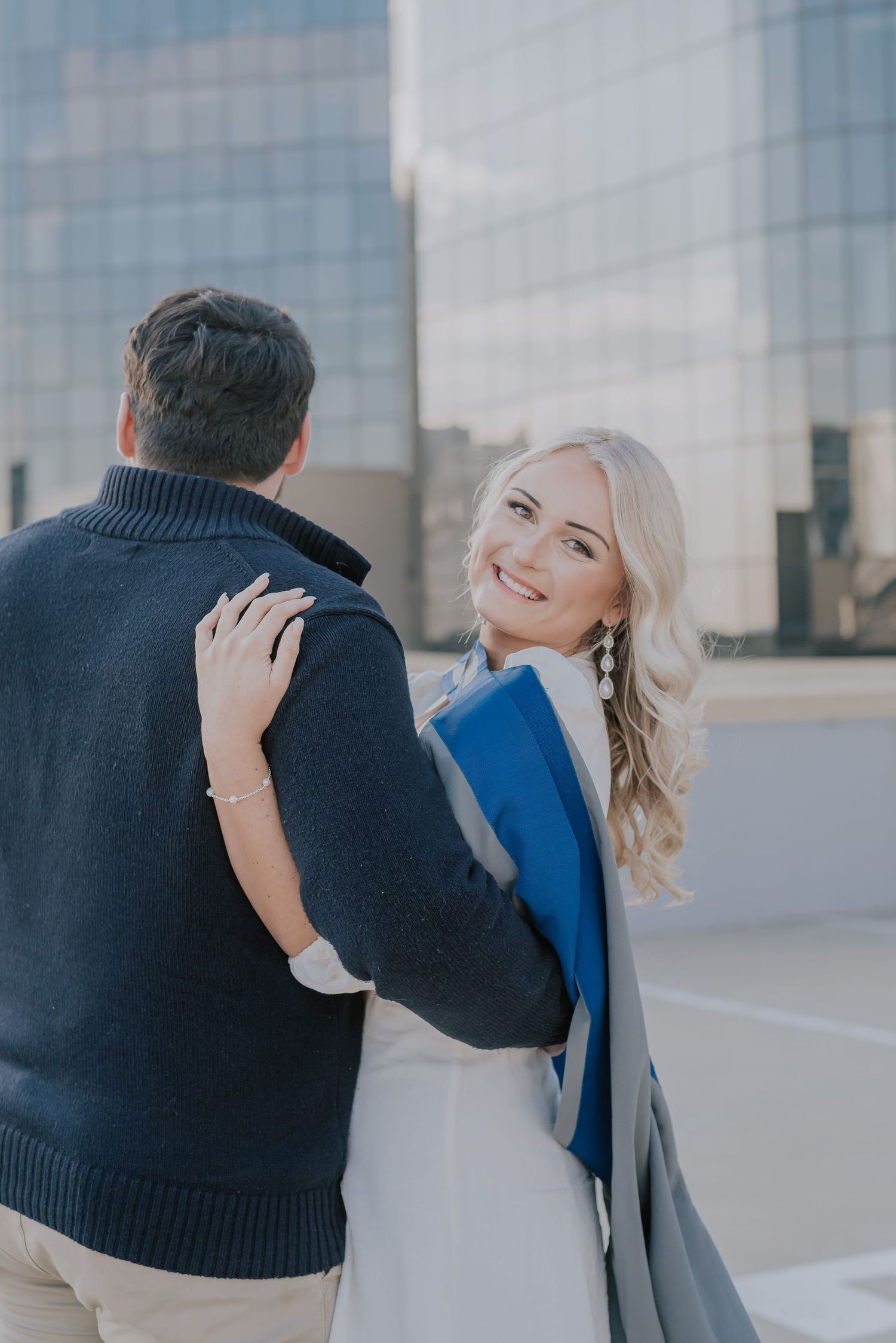 A couple sharing an intimate moment on an urban rooftop with city buildings in background.