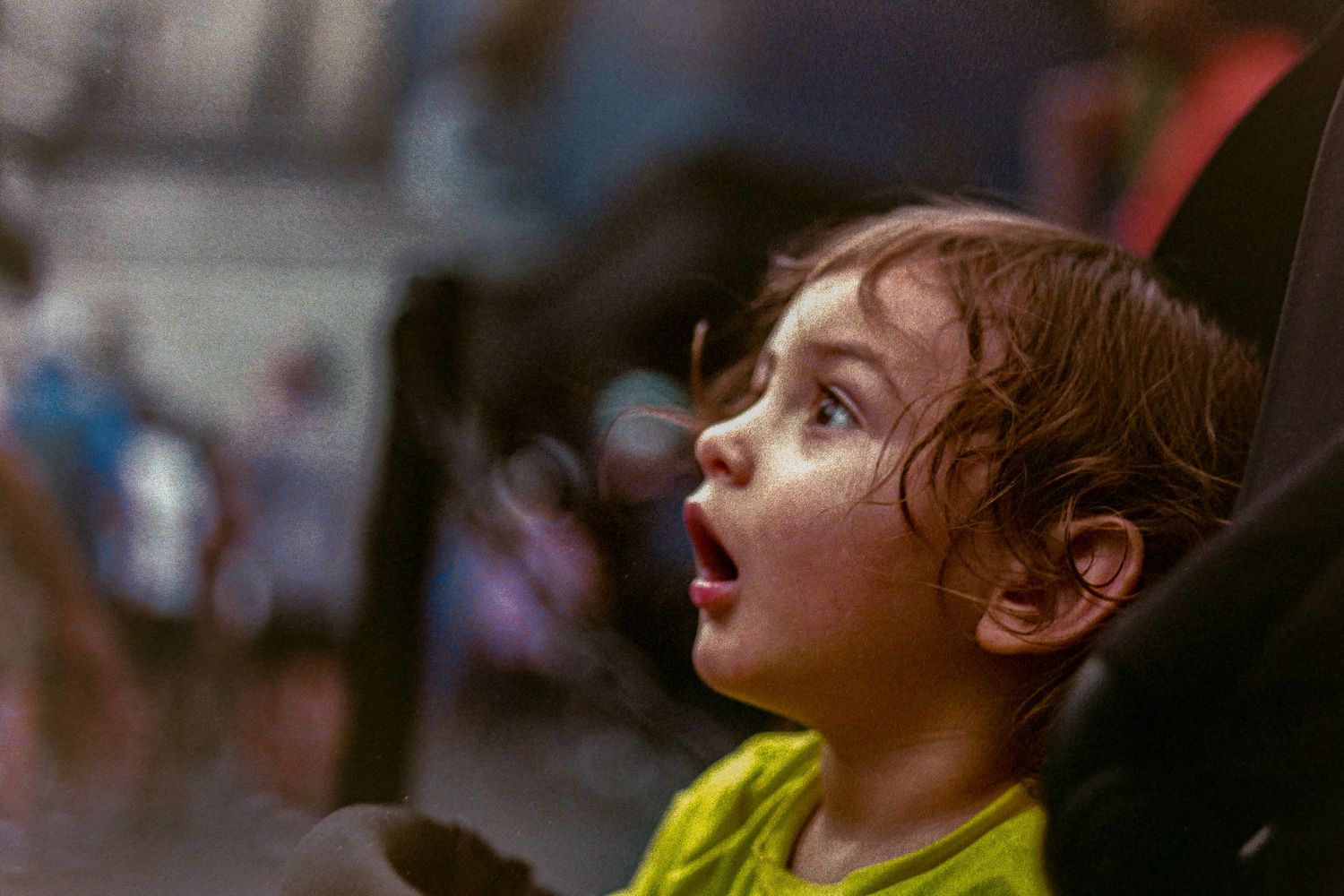 A child in a yellow shirt looking up with amazement and wonder on their face.
