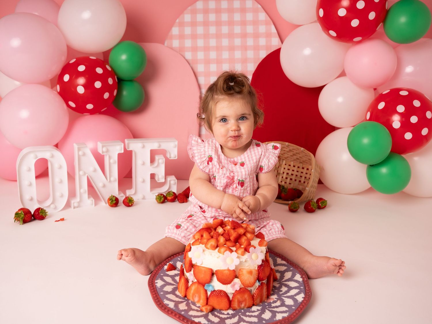 First birthday photoshoot cake smash strawberry theme for one year old girl by newborn photographer in Doncaster.